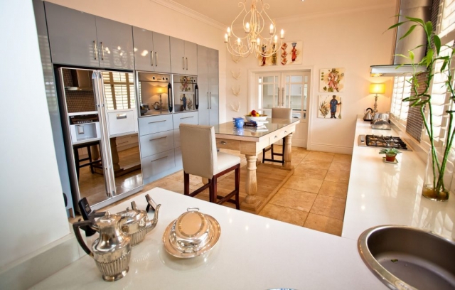 2K high gloss painted kitchen with blue and white cabinets, free standing timber table as island and white ceaserstone counters with a gas hob and prep bowl