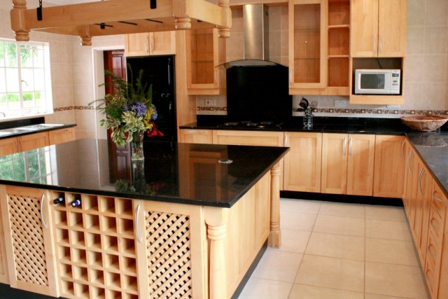 Natural Zimbabwean Jacaranda kitchen with shaker doors, wine rack, turned legs and lattice doors on the vegetable units