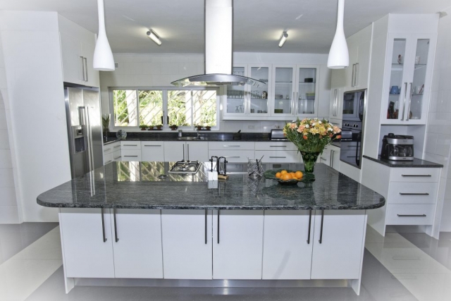 Painted high gloss white kitchen with isand unit with gas and electric hob as well as a double door fridge and double eye level oven