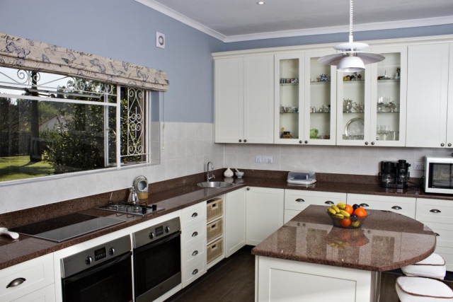 White painted shaker kitchen untis with 2 undercounter ovens and gas and electric hob, central island can seat two people