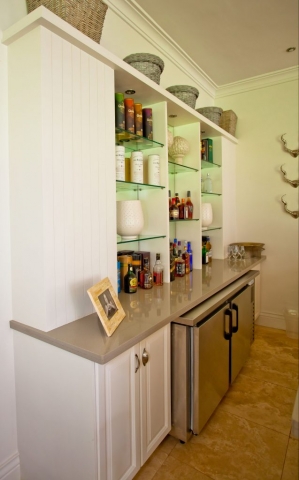 MDF painted white raised panel bar with ceaserstone countertop and glass shelving