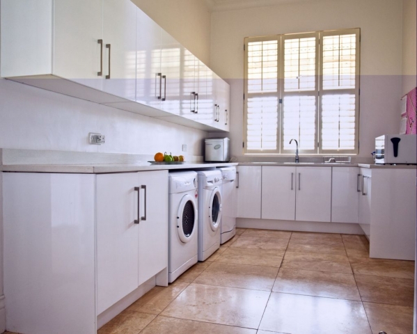 White MDF painted high gloss scullery with double sink washing machine and dryer